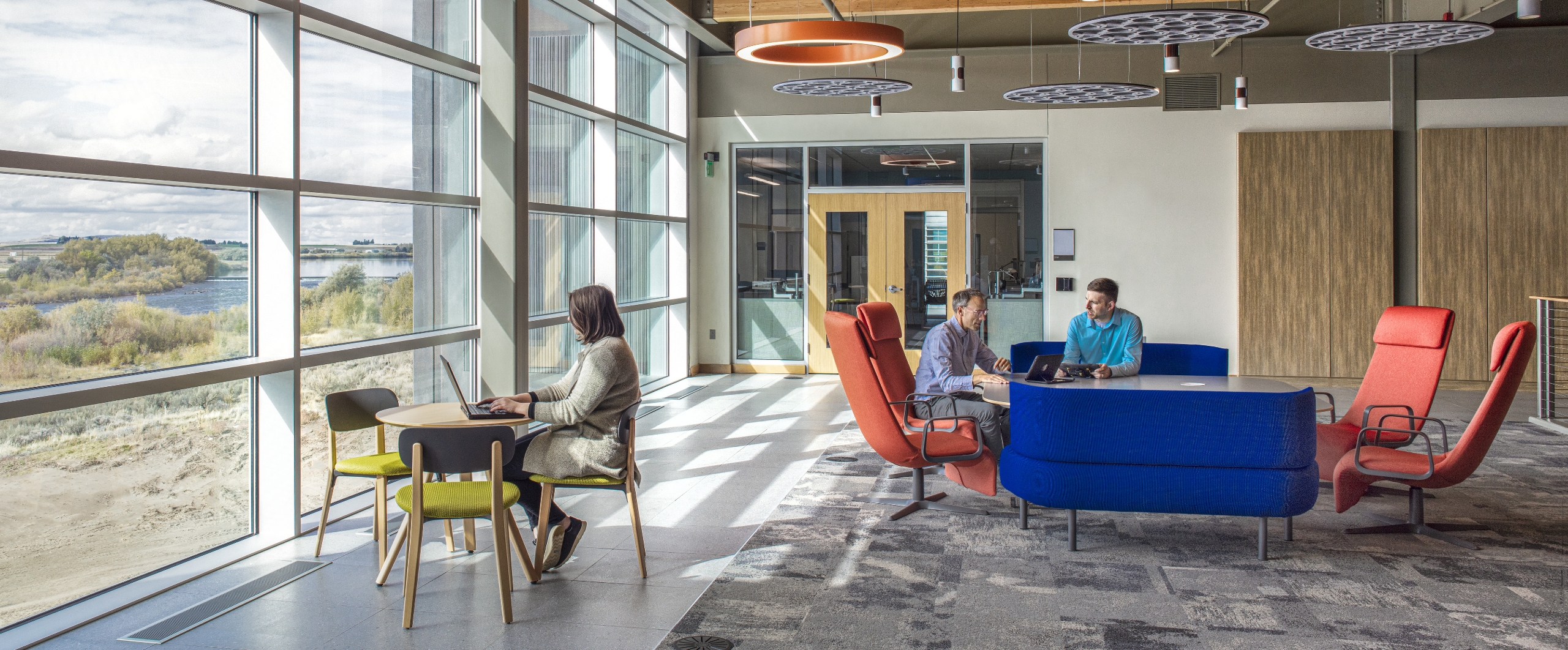 Flad Architects People using an open work area with large windows and views of nature