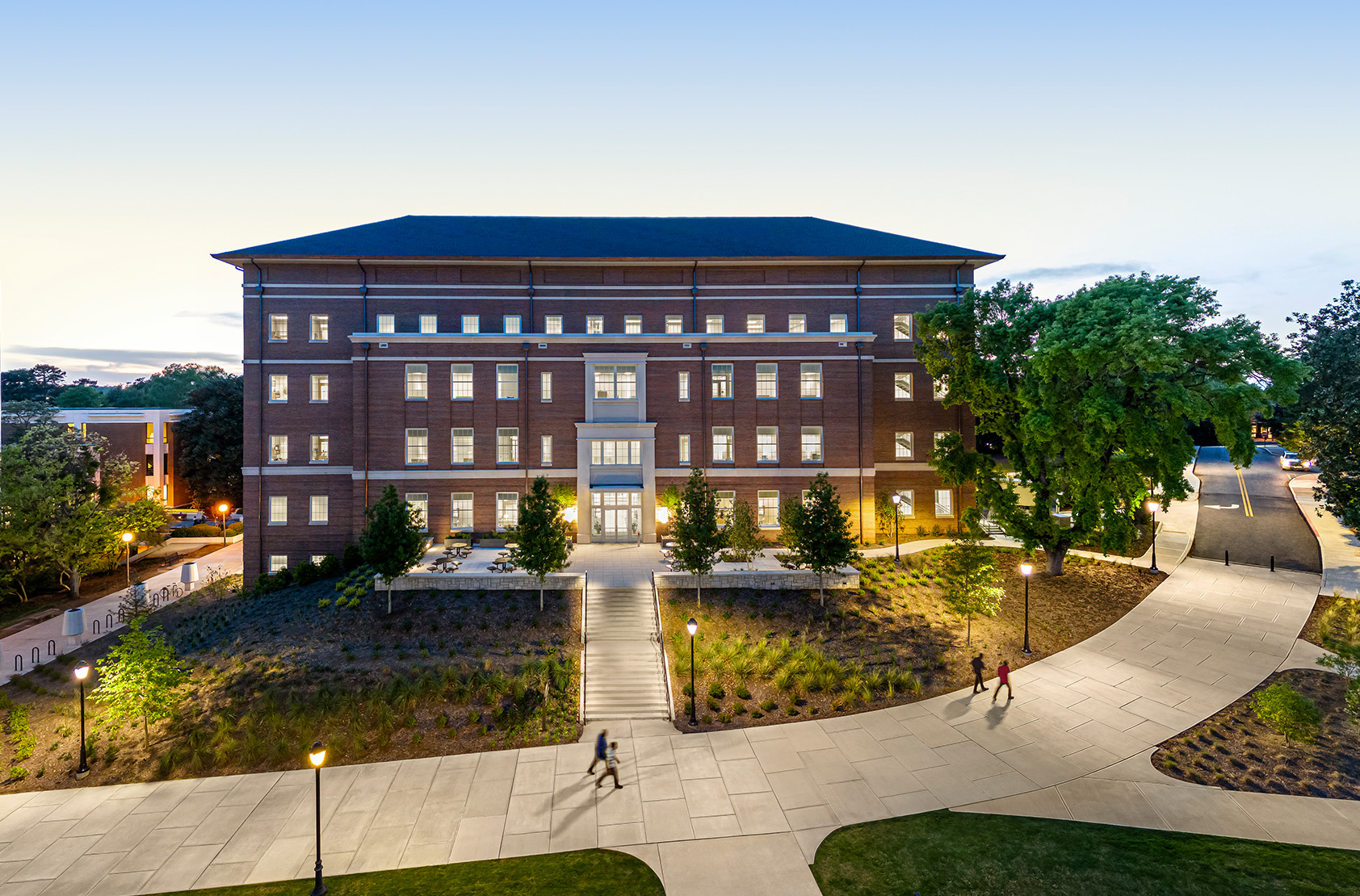 University of Georgia - Poultry Science Complex: Drone captured overall building exterior at dusk captured straight on showing entry and landscape with curved pedestrian path in foreground with people walking